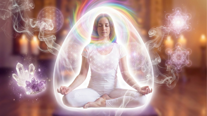 Personne en méditation pratiquant le nettoyage énergétique avec lumière blanche purificatrice et aura colorée